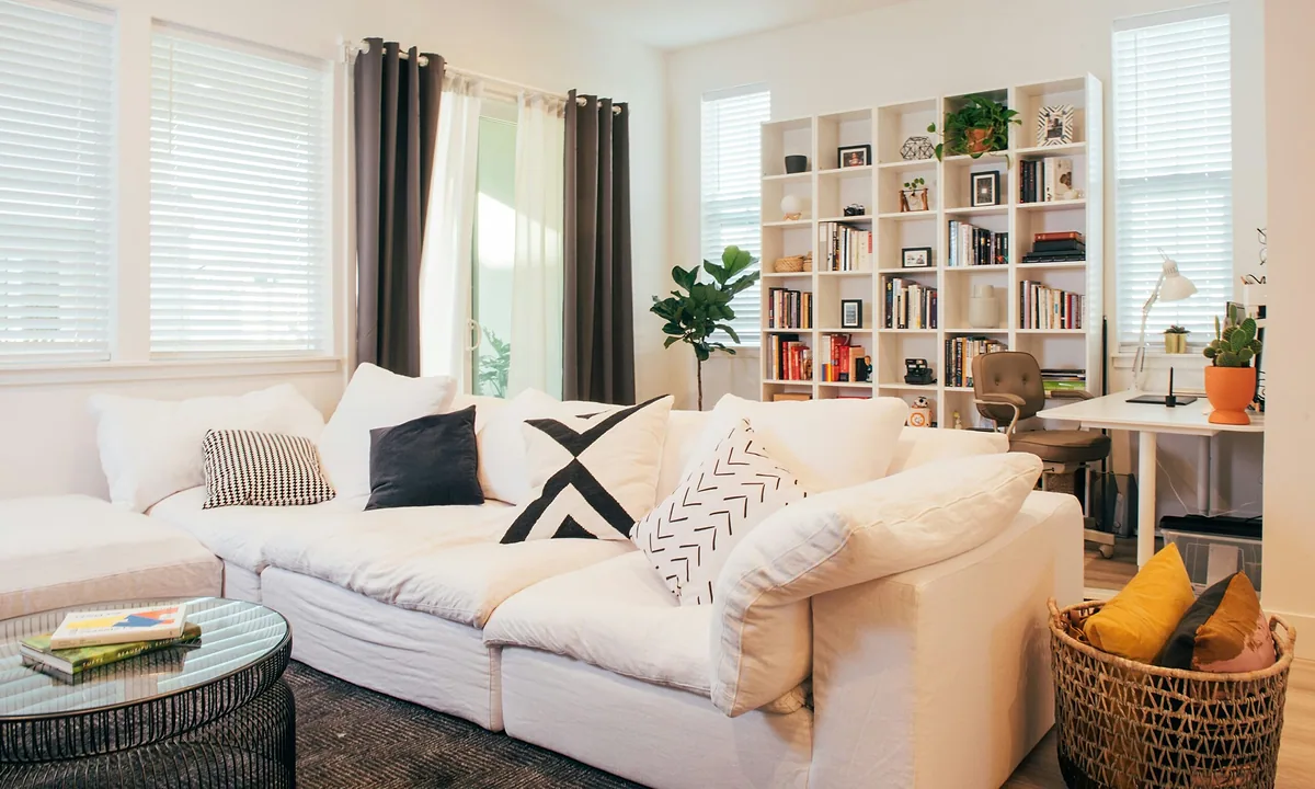 Tidy living room with a white sectional sofa, organized open bookshelves and a storage basket