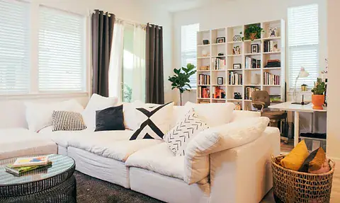 Tidy living room with a white sectional sofa, organized open bookshelves and a storage basket