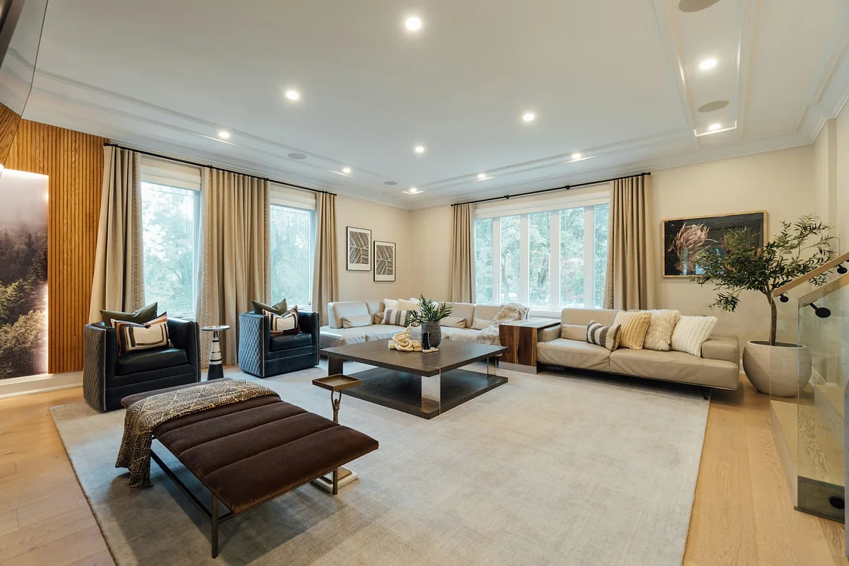 Spacious living room with neutral sofas, floor-length curtains and a large area rug