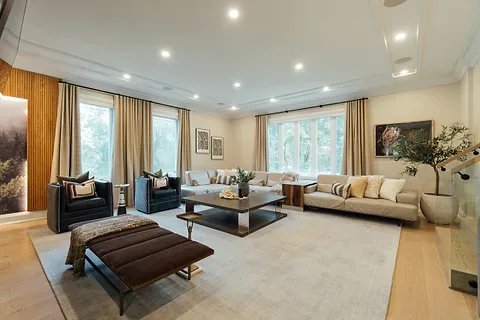 Spacious living room with neutral sofas, floor-length curtains and a large area rug