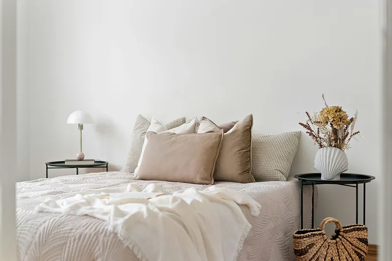 Bed dressed in soft neutral linen bedding with beige pillows and a white throw
