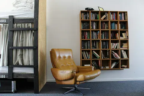 Tan leather armchair beside a wall-mounted bookshelf filled with books
