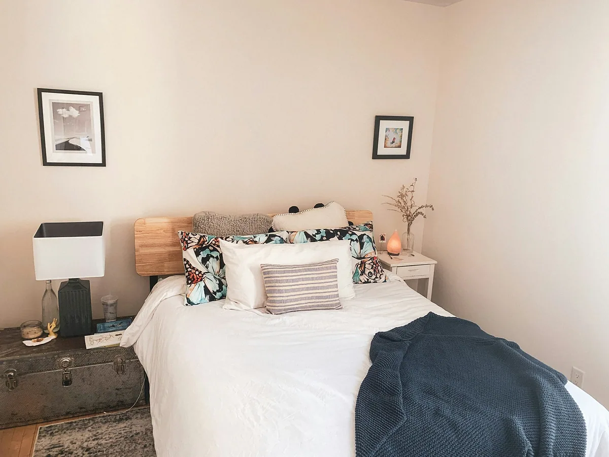 Calm bedroom with a white bed, patterned pillows and a blue knit throw