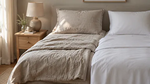 Linen vs cotton sheets: relaxed oat linen and crisp white cotton sheets folded at the foot of a bed